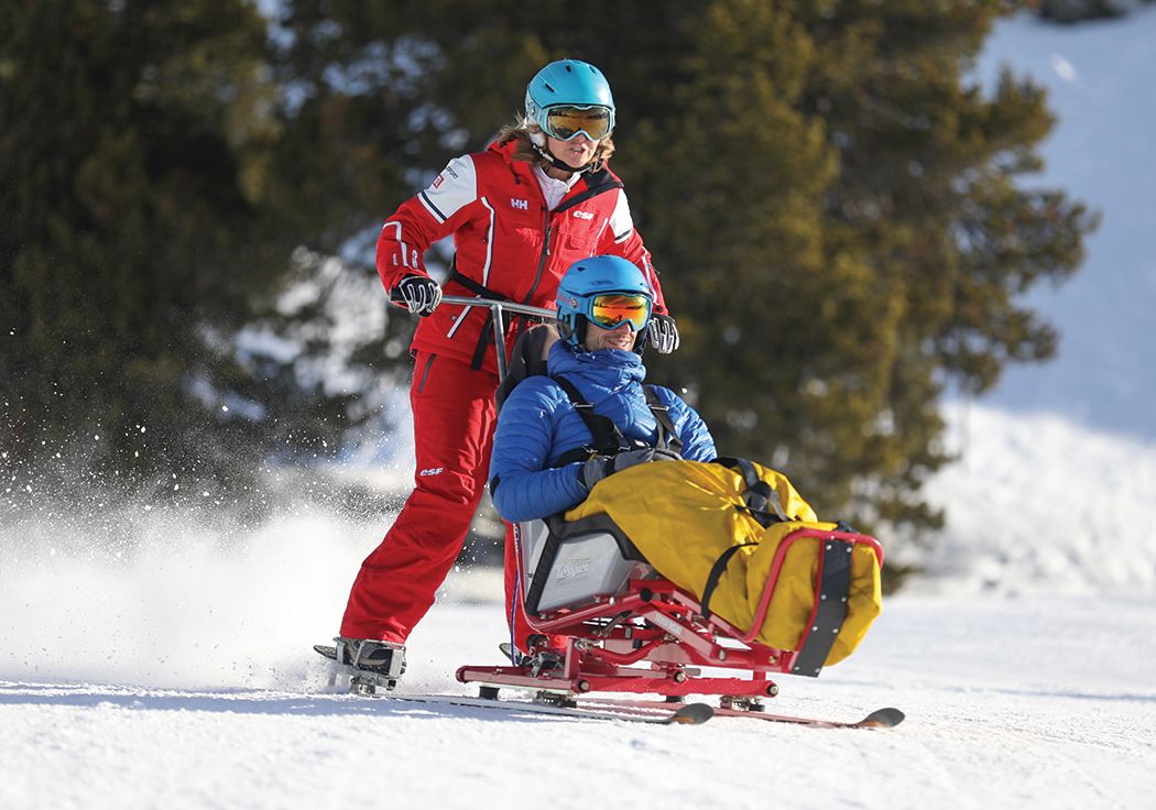 An adult having an assisted sit ski lesson with an esf UK  instructor